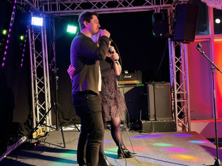 Två deltagare sjunger karaoke tillsammans på en belyst scen.